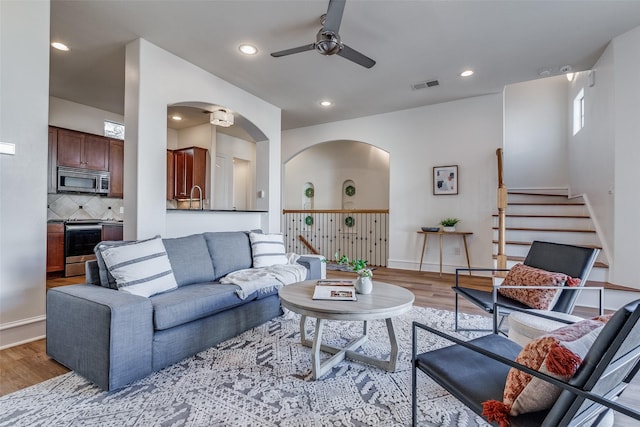 living room featuring ceiling fan, sink, and light hardwood / wood-style flooring