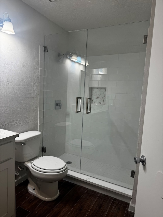 bathroom with vanity, an enclosed shower, a textured ceiling, and hardwood / wood-style flooring