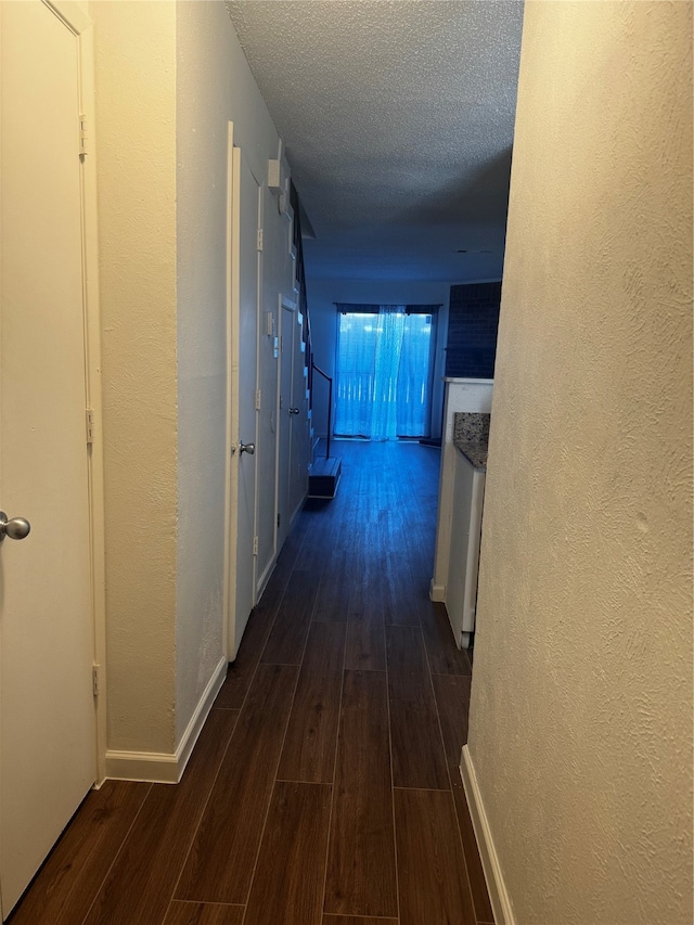 hallway featuring dark wood-type flooring and a textured ceiling