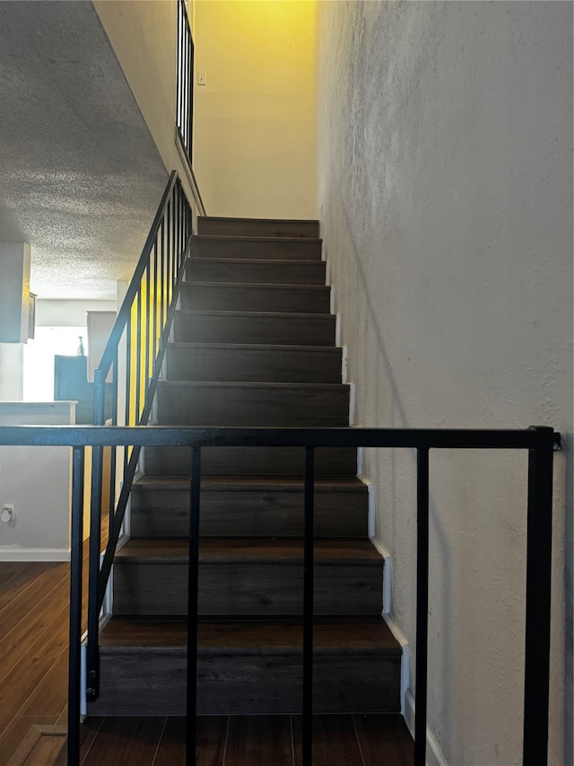 staircase featuring hardwood / wood-style floors and a textured ceiling