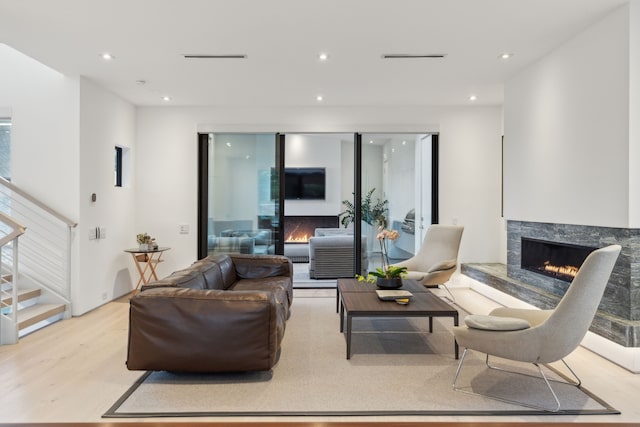 living room featuring a high end fireplace and light hardwood / wood-style floors