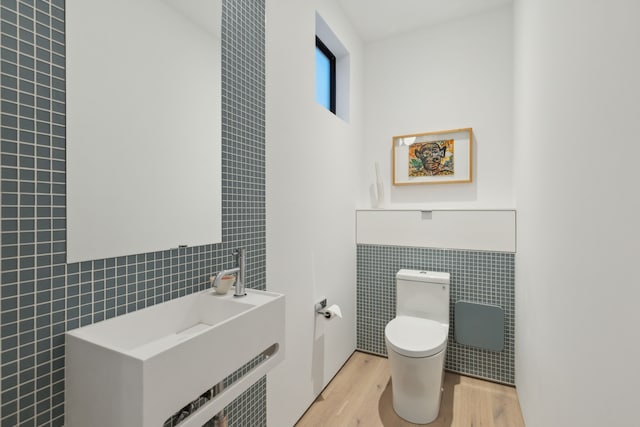 bathroom featuring hardwood / wood-style floors, toilet, and tile walls