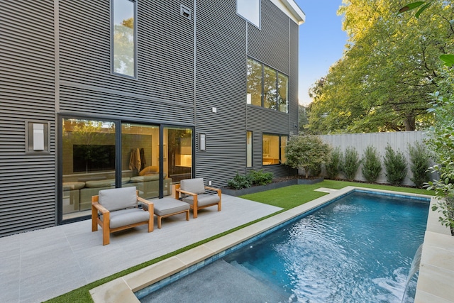 rear view of property with a fenced in pool and a patio area