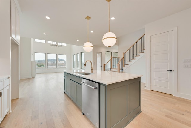 kitchen featuring hanging light fixtures, white cabinetry, sink, and a center island with sink