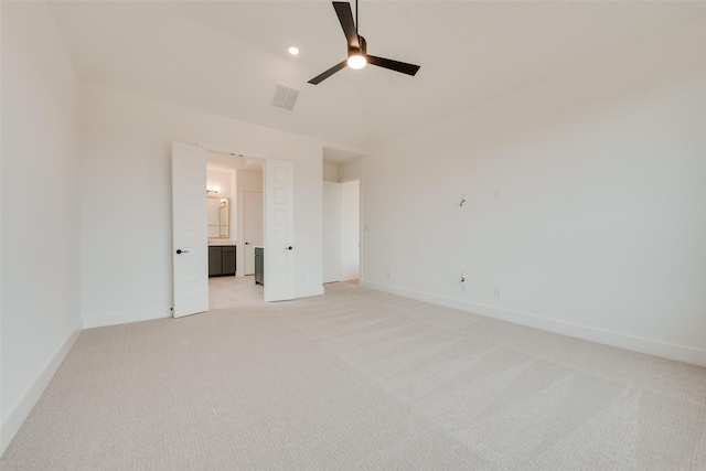 unfurnished bedroom featuring ceiling fan, light colored carpet, and ensuite bath