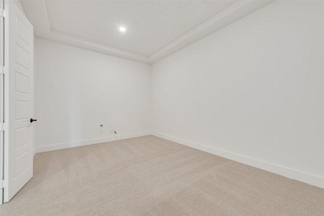 unfurnished room featuring light colored carpet and a tray ceiling