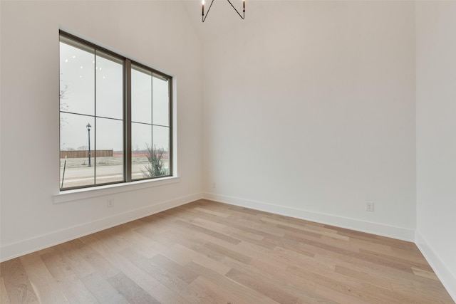 empty room featuring a chandelier and light wood-type flooring