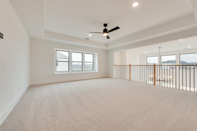 spare room with carpet floors, a wealth of natural light, and a raised ceiling