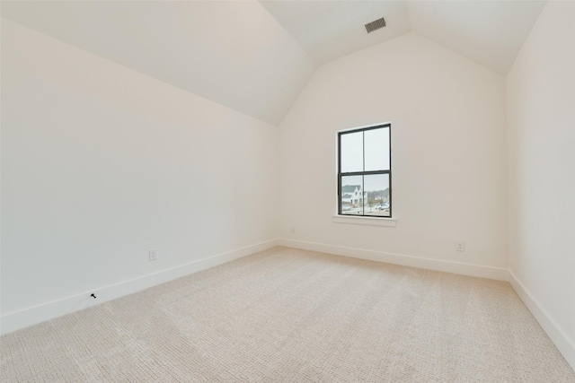 carpeted empty room featuring vaulted ceiling