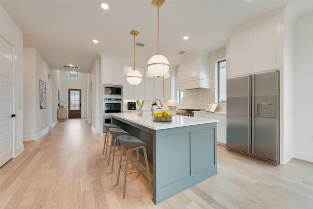 kitchen with stainless steel appliances, custom range hood, pendant lighting, and white cabinets