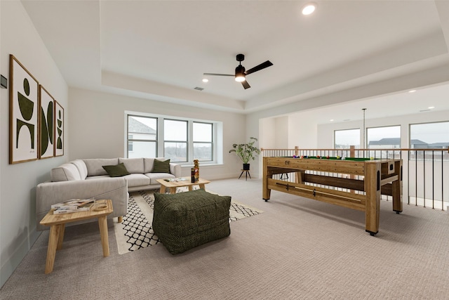 carpeted living room featuring a raised ceiling and ceiling fan