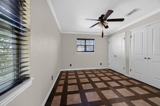 unfurnished bedroom with ceiling fan, ornamental molding, and two closets