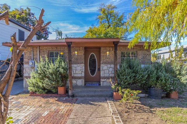 view of exterior entry with stone siding and brick siding