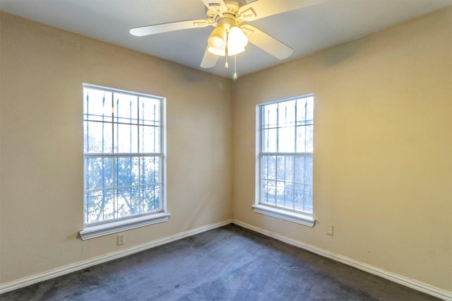 empty room with ceiling fan, plenty of natural light, and dark carpet