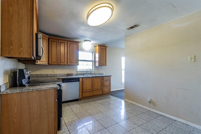 kitchen featuring sink, stainless steel dishwasher, and a textured ceiling