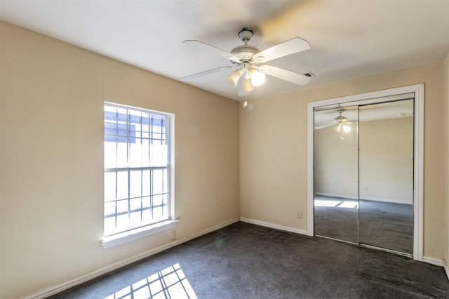 unfurnished bedroom featuring dark colored carpet, ceiling fan, and a closet