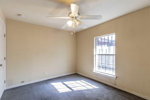 unfurnished room with dark colored carpet and ceiling fan