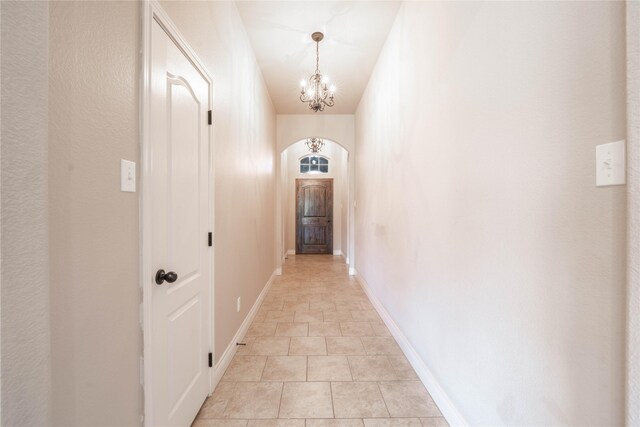 hallway with a chandelier and light tile patterned flooring