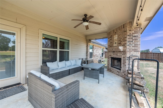 view of patio with an outdoor living space with a fireplace and ceiling fan