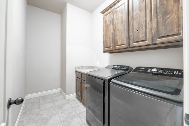 laundry area featuring cabinets, washing machine and dryer, and light tile patterned floors