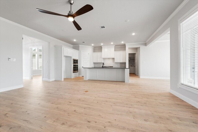 unfurnished living room featuring crown molding, sink, ceiling fan, and light wood-type flooring