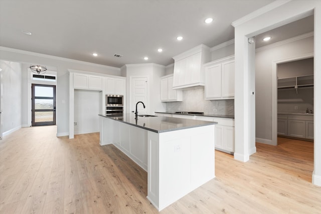 kitchen featuring sink, white cabinetry, an island with sink, and light hardwood / wood-style flooring