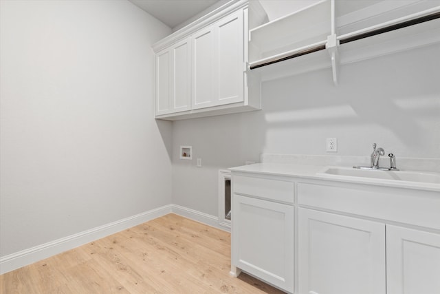 washroom with cabinets, washer hookup, light hardwood / wood-style floors, and sink