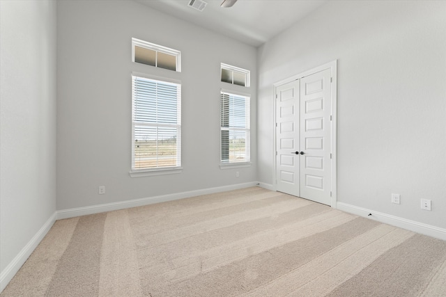 unfurnished bedroom featuring light carpet and a closet