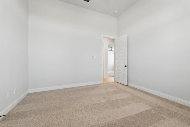 unfurnished room with light colored carpet and a towering ceiling