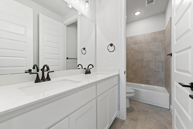 full bathroom featuring vanity, tiled shower / bath combo, and toilet