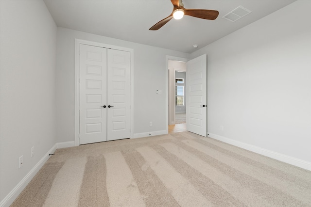 unfurnished bedroom with light carpet, a closet, and ceiling fan