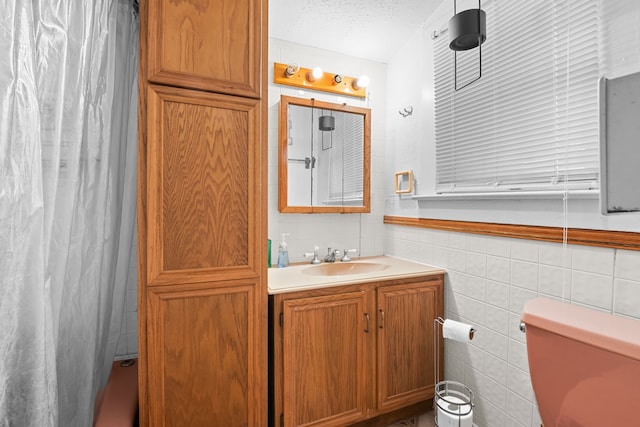 bathroom with vanity, a textured ceiling, toilet, and tile walls