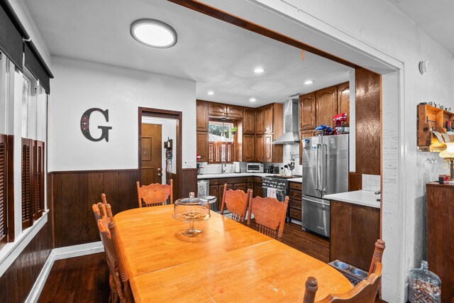 dining area with dark wood-type flooring and wooden walls