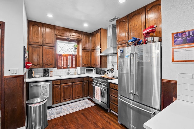 kitchen featuring sink, wall chimney exhaust hood, dark hardwood / wood-style floors, decorative backsplash, and appliances with stainless steel finishes