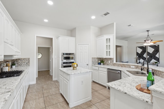 kitchen with decorative backsplash, a kitchen island, light stone counters, custom range hood, and stainless steel appliances