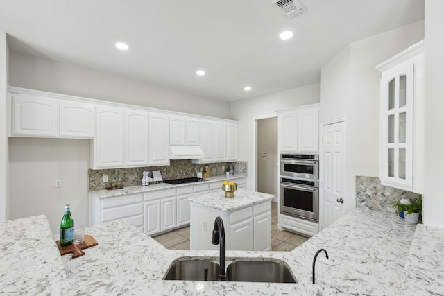 kitchen featuring white cabinetry, sink, stainless steel double oven, tasteful backsplash, and light stone counters