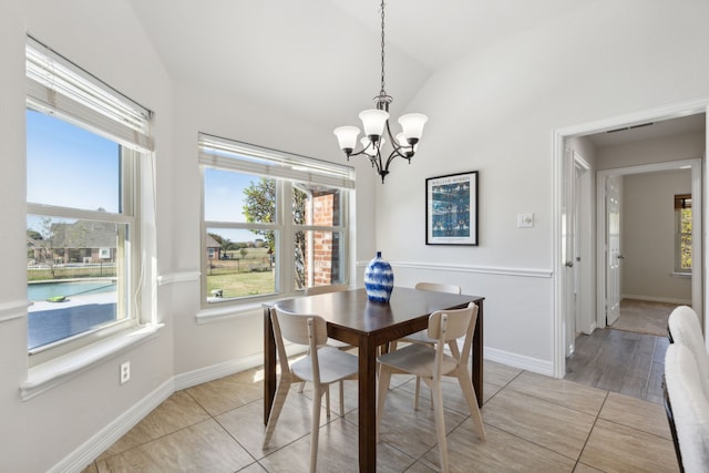 dining space featuring a notable chandelier, light wood-type flooring, a wealth of natural light, and vaulted ceiling