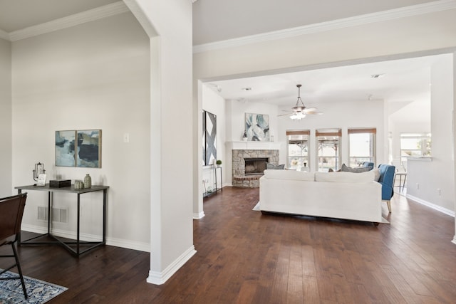 living room with ornamental molding, a stone fireplace, ceiling fan, and dark wood-type flooring