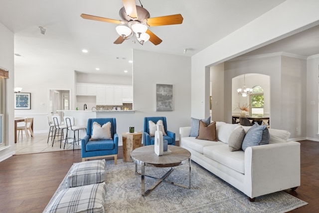 living room featuring hardwood / wood-style flooring, ceiling fan with notable chandelier, and crown molding