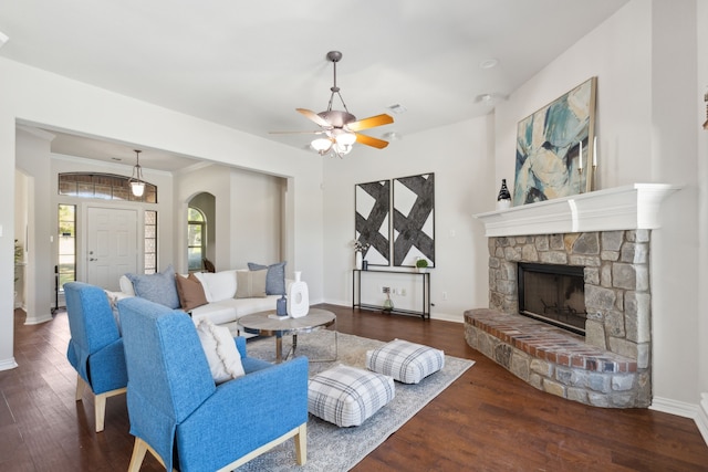 living room featuring ceiling fan, a fireplace, dark hardwood / wood-style floors, and ornamental molding