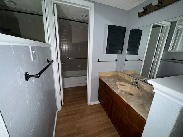 full bathroom featuring vanity, tiled shower / bath, toilet, a textured ceiling, and wood-type flooring