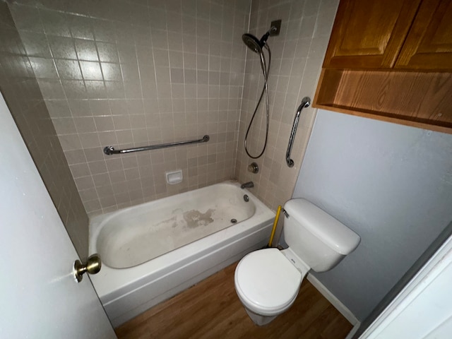 bathroom featuring toilet, wood-type flooring, and tiled shower / bath