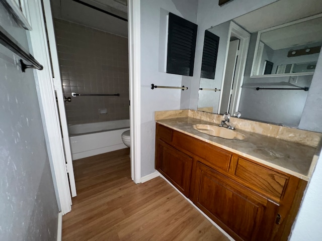 full bathroom featuring hardwood / wood-style floors, vanity, toilet, and tiled shower / bath