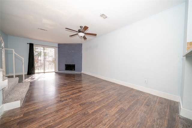 unfurnished living room with ceiling fan, dark wood-type flooring, and a brick fireplace