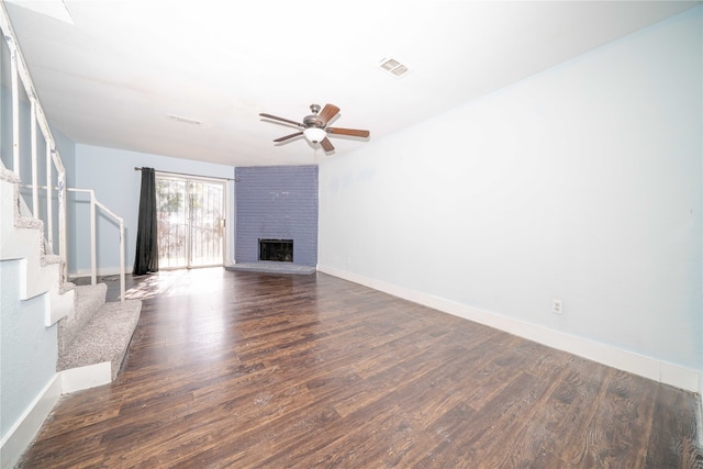 unfurnished living room with ceiling fan, dark wood-type flooring, and a brick fireplace