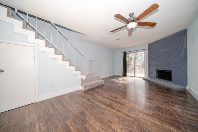 unfurnished living room featuring dark hardwood / wood-style floors, ceiling fan, and a brick fireplace