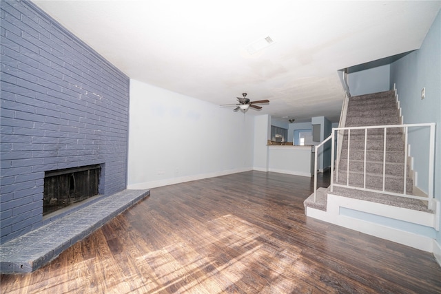 unfurnished living room featuring a fireplace, dark hardwood / wood-style floors, and ceiling fan