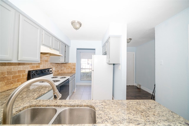 kitchen with light wood-type flooring, white appliances, light stone countertops, and sink