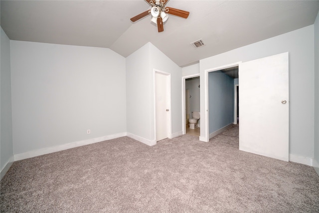 unfurnished bedroom featuring carpet flooring, connected bathroom, vaulted ceiling, and ceiling fan