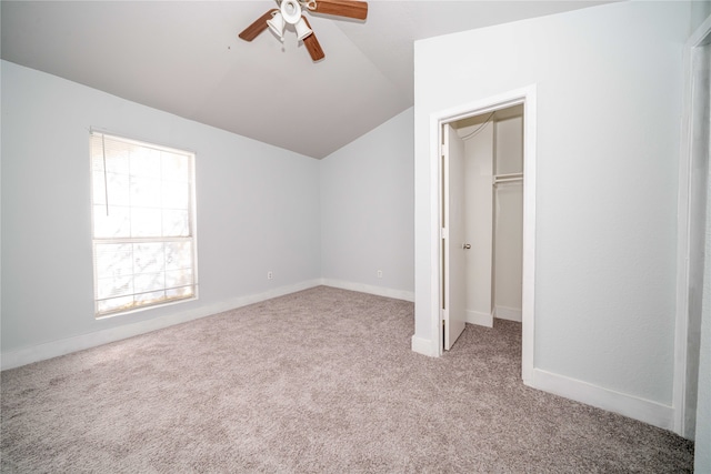 unfurnished bedroom featuring lofted ceiling, light carpet, a walk in closet, ceiling fan, and a closet